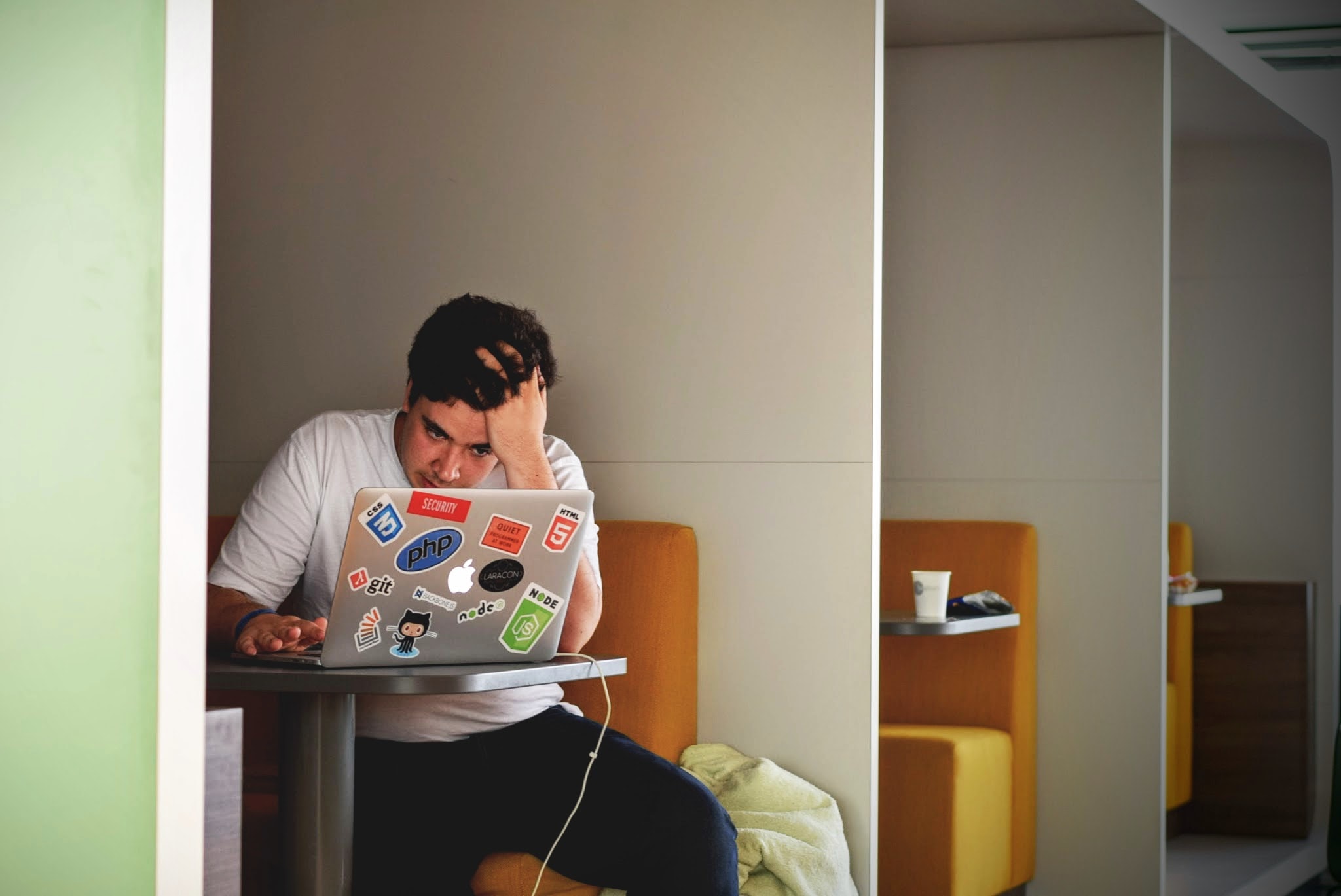 Frustrated man on laptop in cubicle.