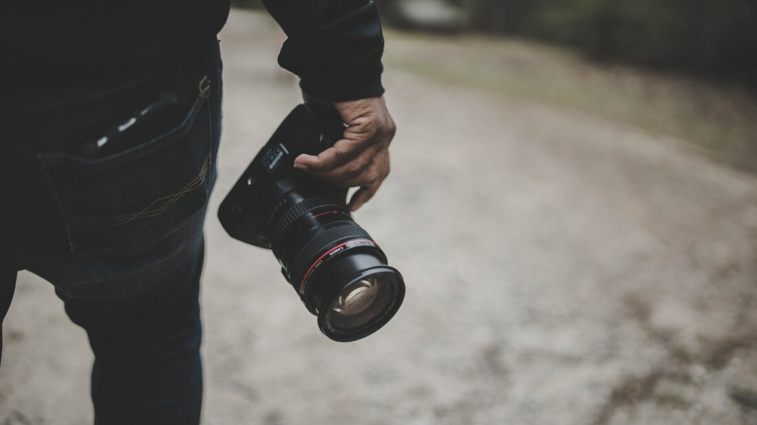Close up image of African American man's hands holding a Canon Mirrorless Camera